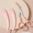Pink eyebrow trimming knife set with curved blades and a small scissor comb for precise eyebrow grooming