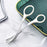 White handled eyebrow trimming knife with comb blade on marble surface near green tray
