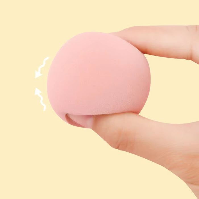 Hand holding a pink makeup blending sponge showing its soft texture and flexibility