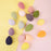 Collection of colorful makeup blending sponge in various pastel and vibrant shades on yellow and pink background