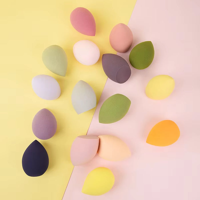 Collection of colorful makeup blending sponge in various pastel and vibrant shades on yellow and pink background